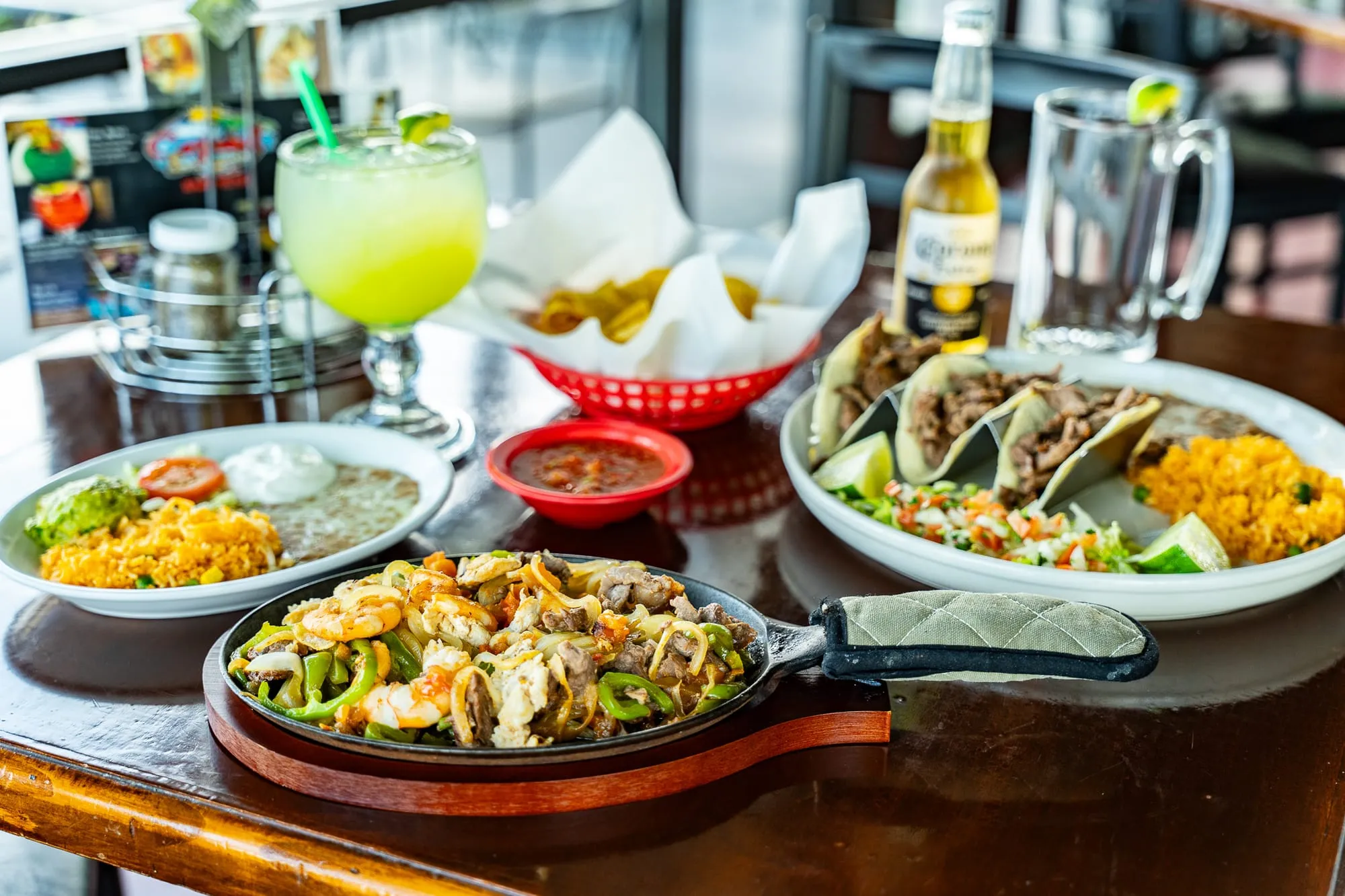 A loaded Cozumel fajita platter with grilled meat, peppers, and onions beside a margarita