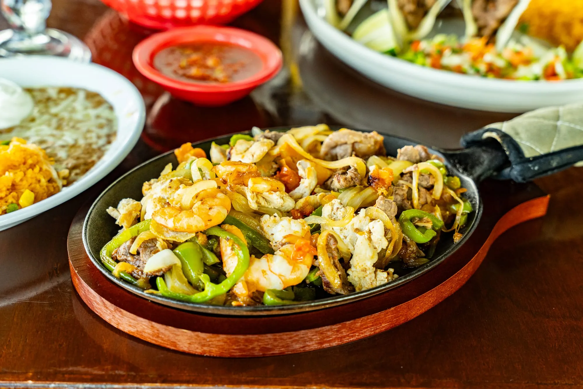 A sizzling skillet of Cozumel fajitas with peppers and onions, served with rice and beans