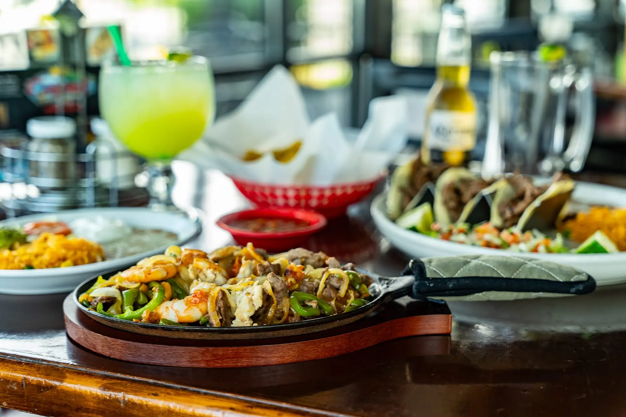 A spread of Cozumel fajitas, street tacos, and a fresh lime margarita on the table
