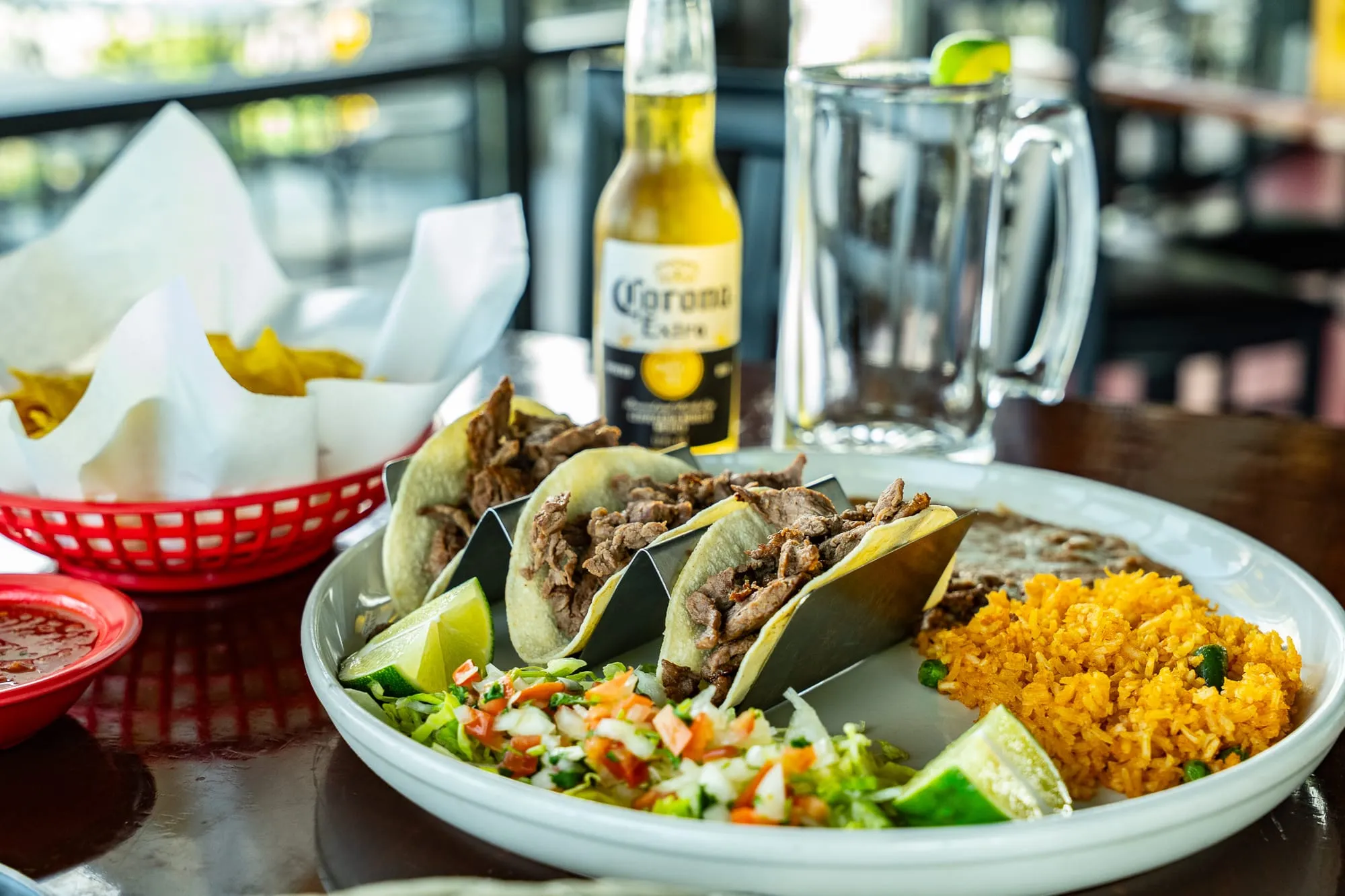 A plate of authentic Cozumel street tacos with cilantro, onion, and lime, served with rice and beans