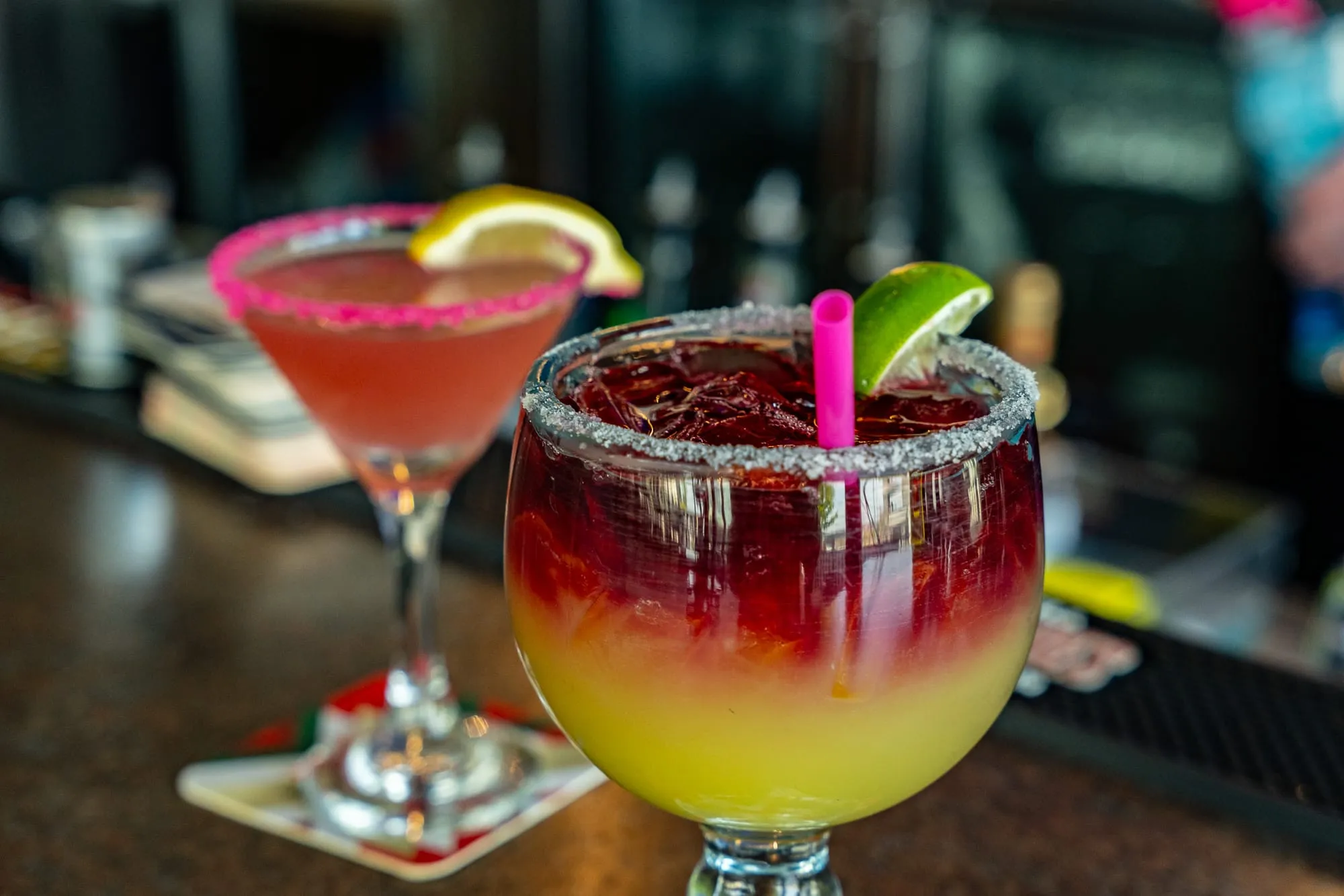 A vibrant pomegranate sunrise cocktail garnished with lime at Cozumel