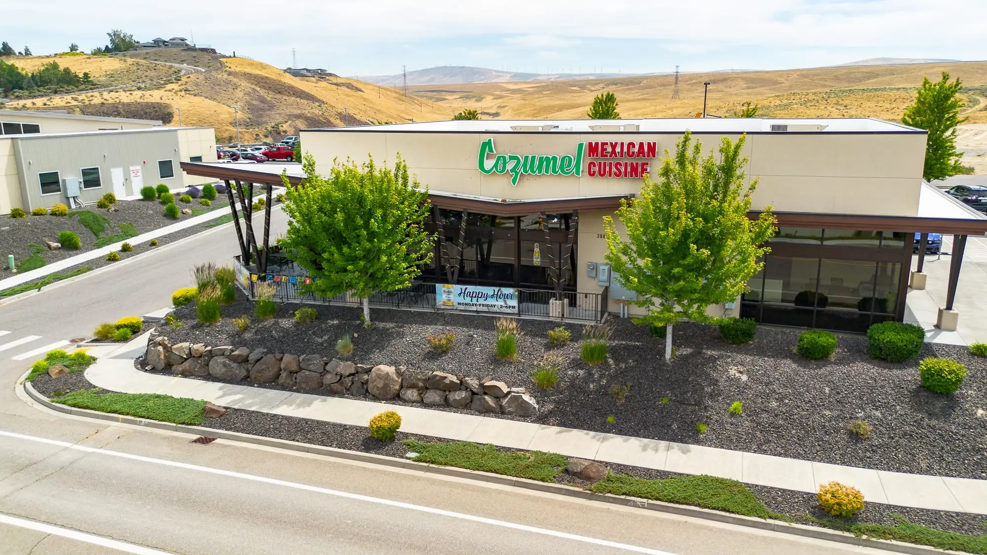 Aerial view of Cozumel Mexican Cuisine in Kennewick, WA, with its green Cozumel sign, covered patio, and landscaped entry