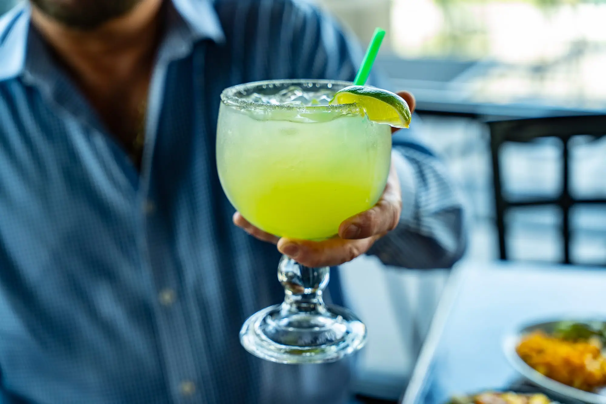 A Cozumel host presenting a freshly made margarita tableside